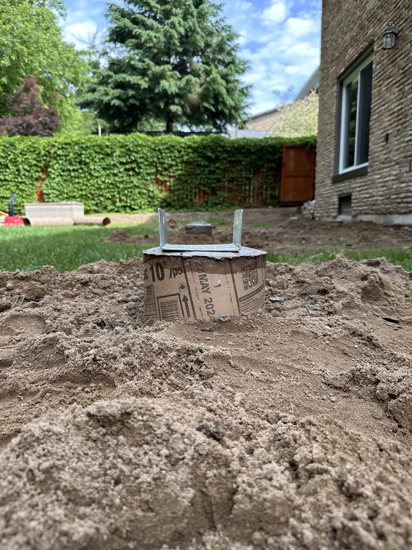 Freshly dug deck pier hole with a gravel base ready for concrete