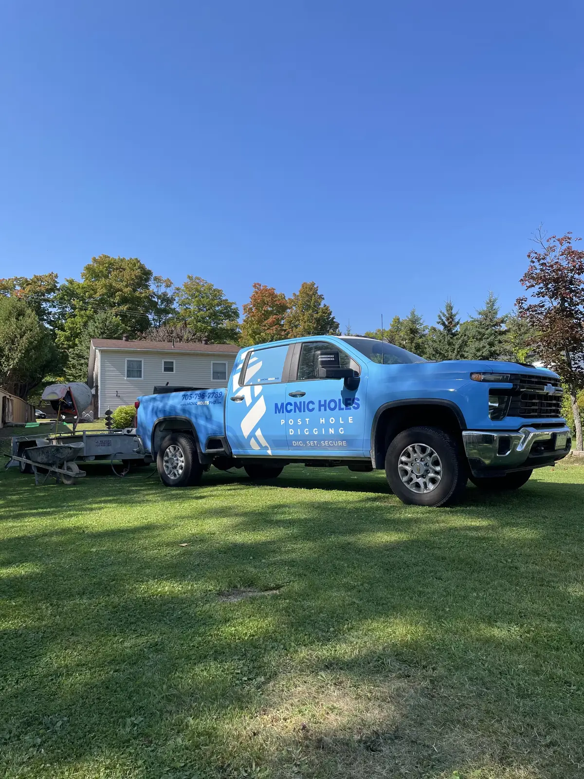 McNic Holes branded blue pickup truck and trailer at work